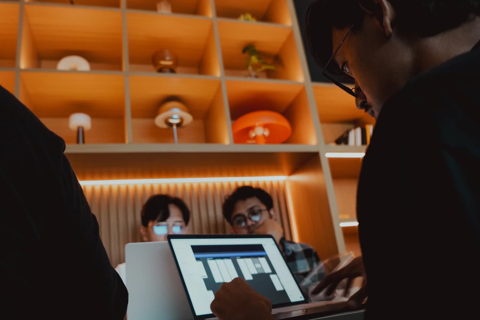 Designers gathered around a laptop, discussing work in a warmly lit studio